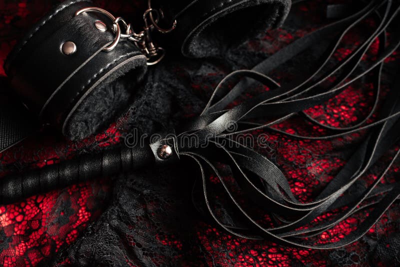 Handcuffs and a whip with women`s underwear. Concept of sex toys for BDSM with submission and domination. Handcuffs and a whip with women`s underwear. Concept of sex toys for BDSM with submission and domination